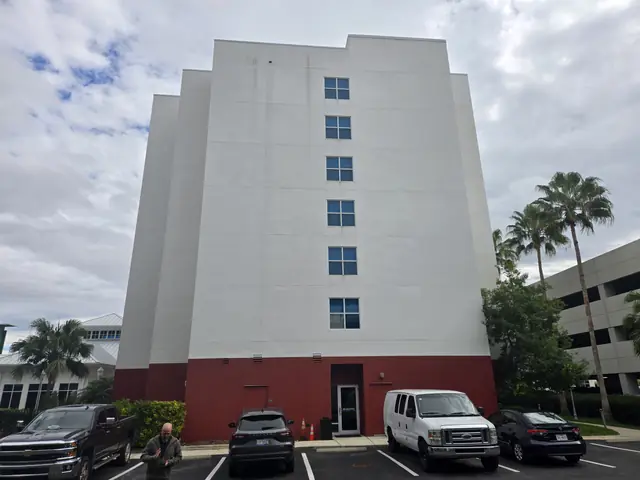 Multi-story hotel exterior with visible staining on the upper walls before drone cleaning