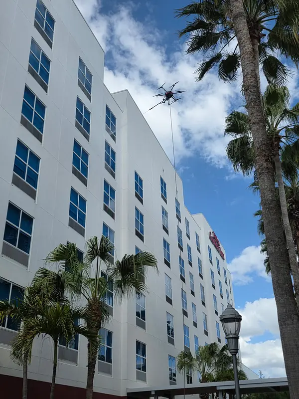 Cleaning drone with a hose line working on the upper floors of the hotel