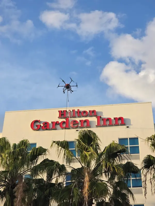 Cleaning drone and hose line flying above a Hilton Garden Inn sign